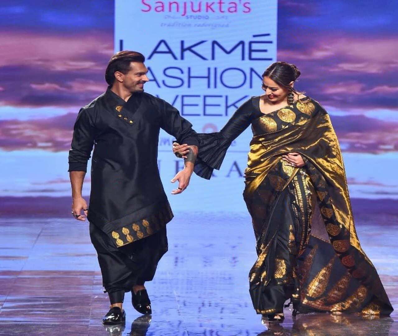 Here, the two are seen walking the ramp for a designer and exuding power and aura, and setting major couple goals! They are looking radiant, regal and resplendent while twinning in a black saree and dhoti